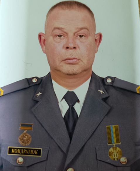 Чоловік у військовій формі з медалями та іменним жетоном дивиться прямо в камеру.
