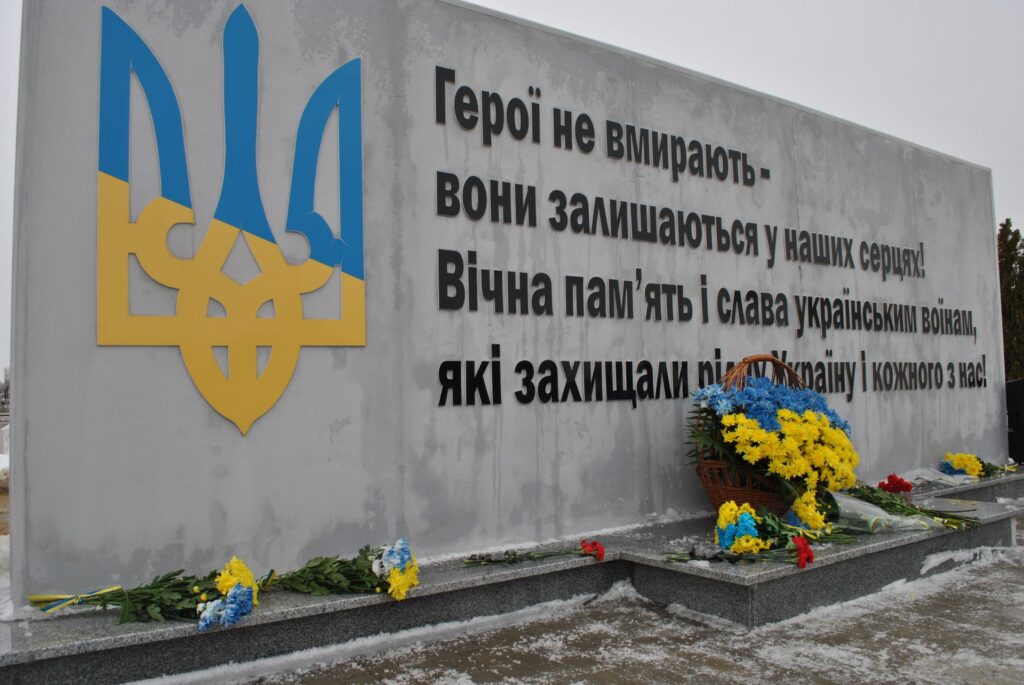 Пам'ятна плита з українським гербом та квітами.