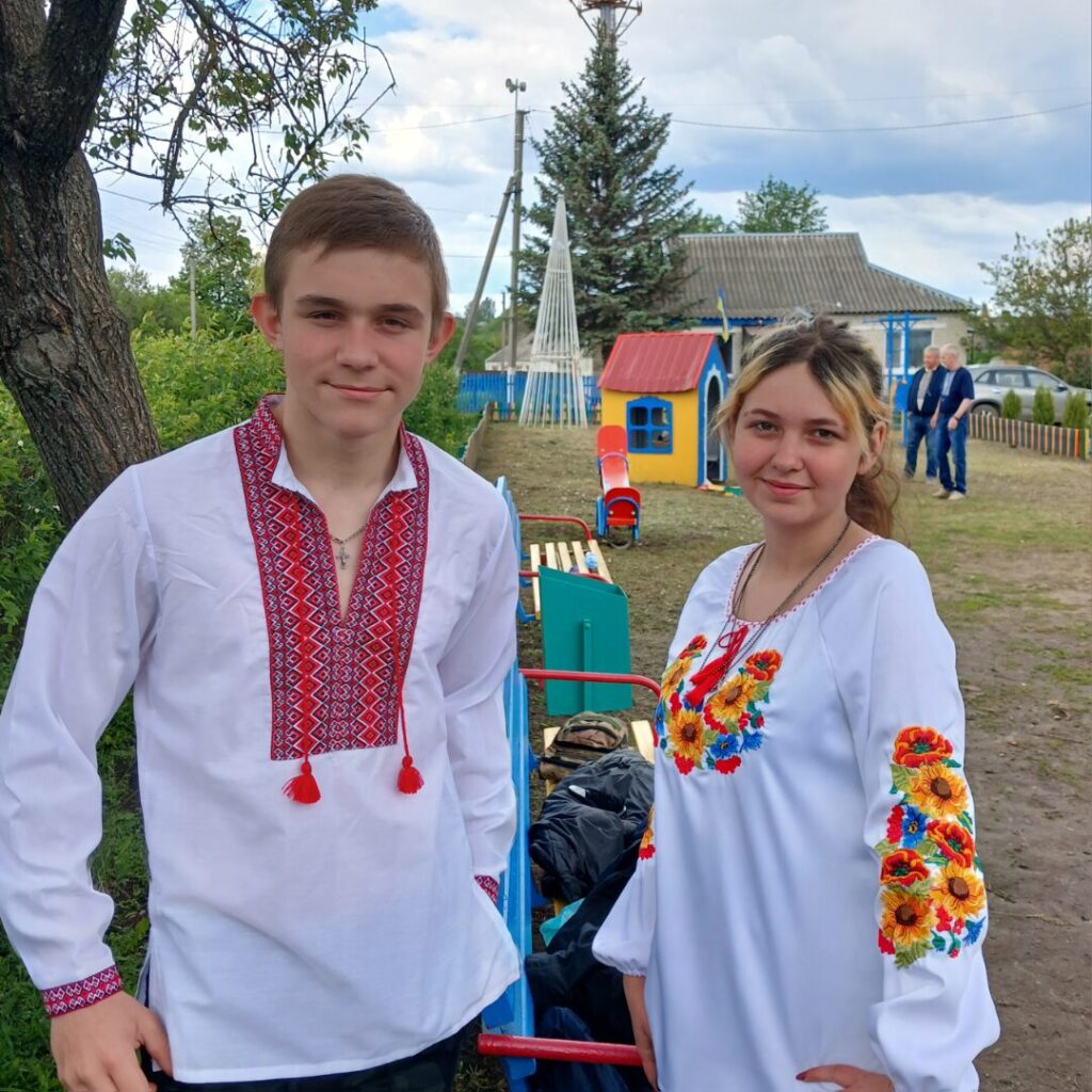 Парубок і дівчина в українському національному одязі стоять біля дитячого майданчика.