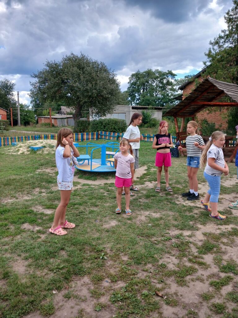 Дівчатка стоять у колі на дитячому майданчику.