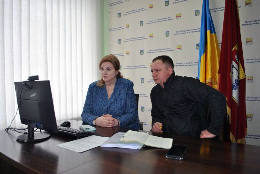 Жінка та чоловік сидять за столом і дивляться на монітор комп'ютера.