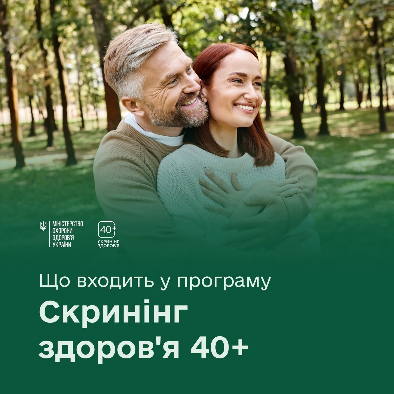 Літній чоловік обіймає жінку, вони обидва посміхаються й дивляться в одному напрямку на тлі лісу.