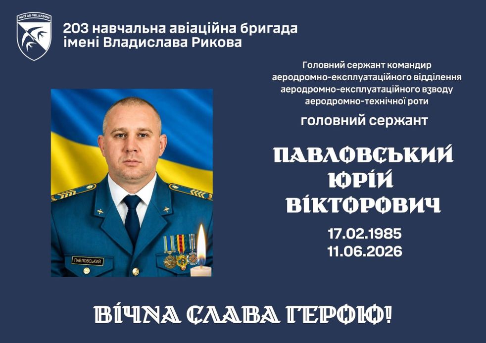 Головний сержант Павлвський Юрій Вікторович у військовій формі стоїть на тлі українського прапора.