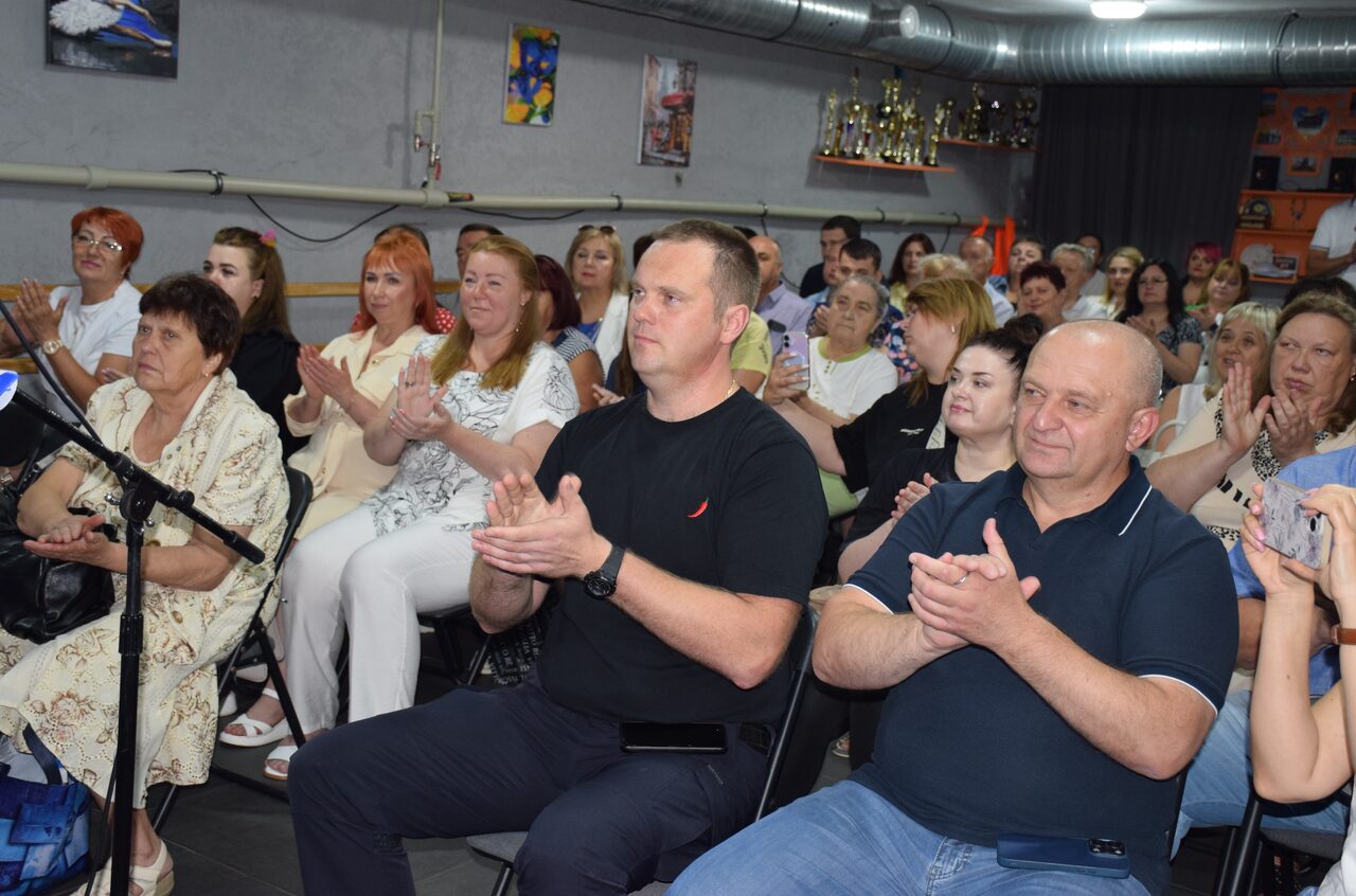 Група людей сидить у залі та оплескує.
