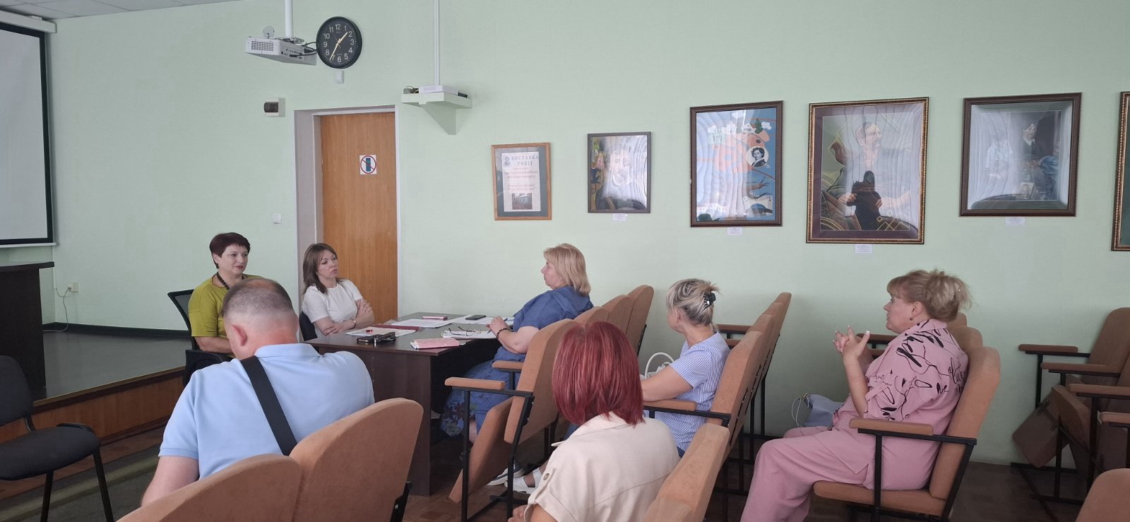 Група людей сидить у кріслах та за столом під час дискусії в кім