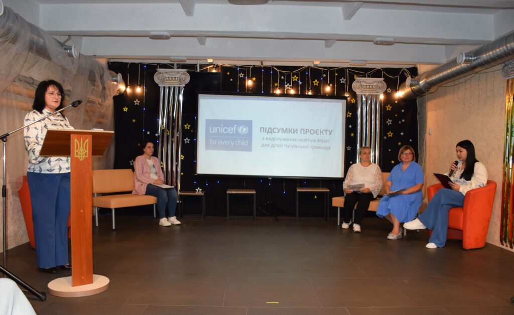 Жінка виступає за трибуною з тризубом на заході, присвяченому підсумкам проекту ЮНІСЕФ з надолуження освітніх втрат для дітей Чугуївської громади.