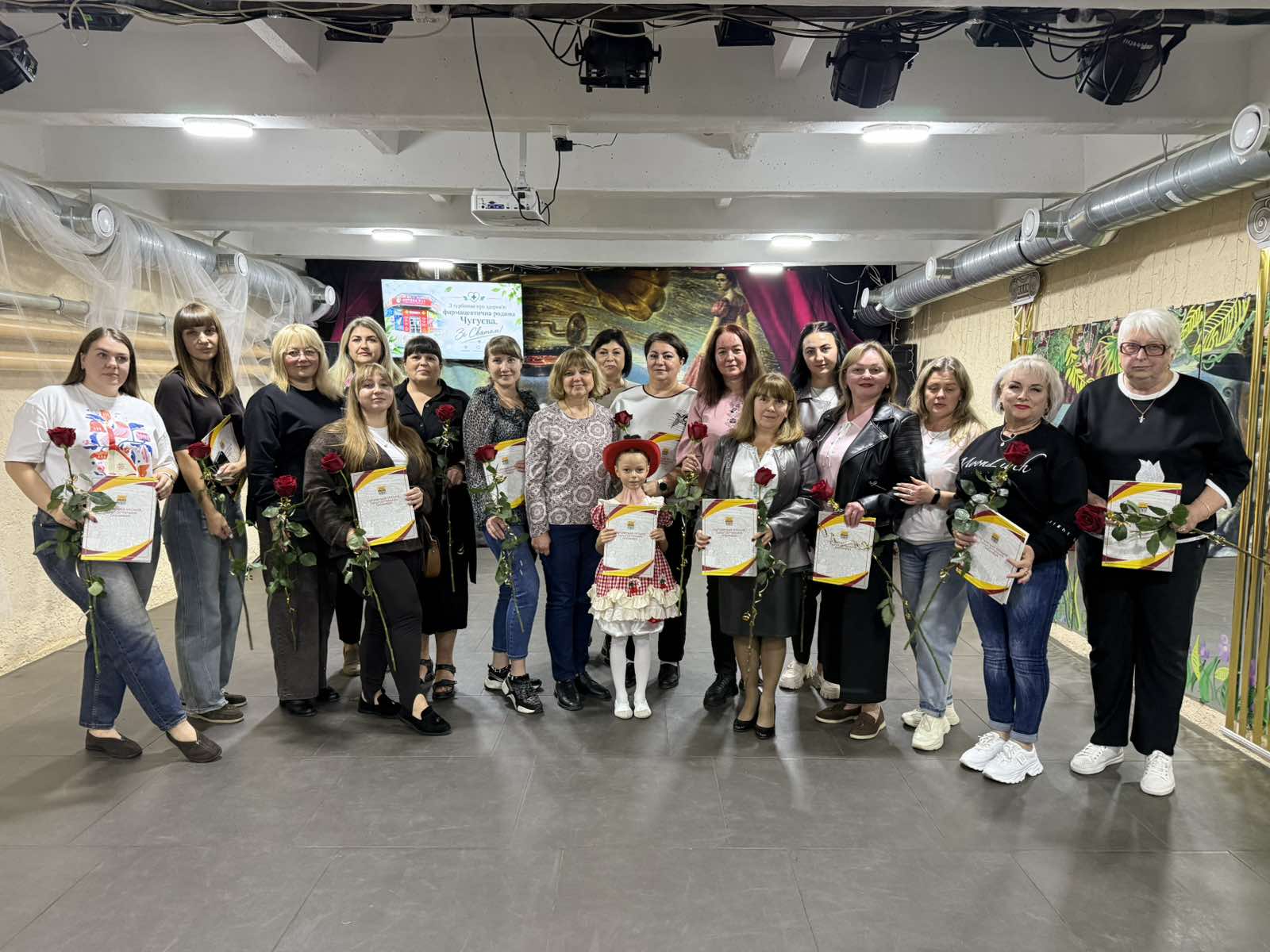 Група людей тримає в руках сертифікати та червоні троянди.