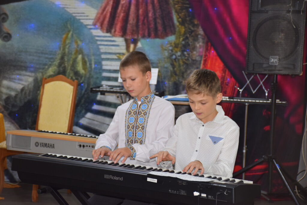 Два хлопчики грають на електронних піаніно Roland та Yamaha на сцені.