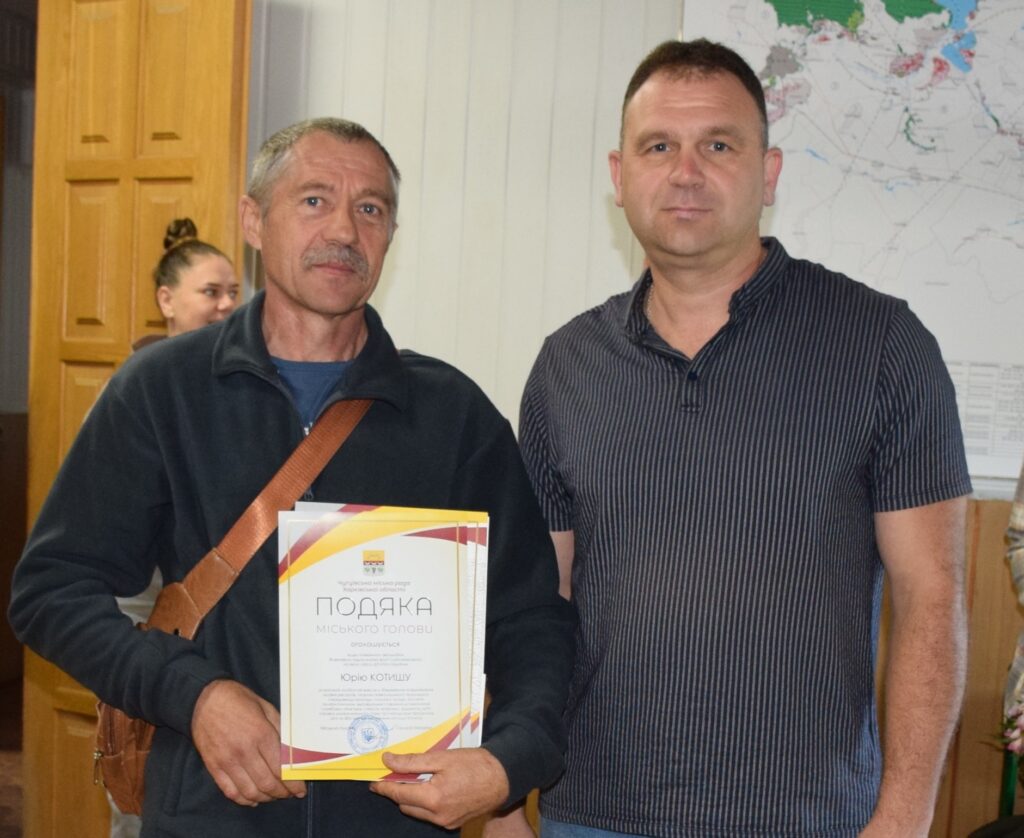 Чоловік тримає подяку від міського голови, а поруч стоїть інший чоловік.