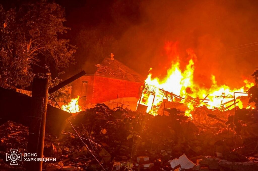 Нічний пожежний інцидент у Харківській області, де вогонь охопив будівлю та навколишні уламки, з логотипом ДСНС.