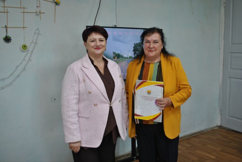 Дві жінки стоять поруч, одна з них тримає грамоту з написом «Вітаємо Мічу Тетяну Іванівну».