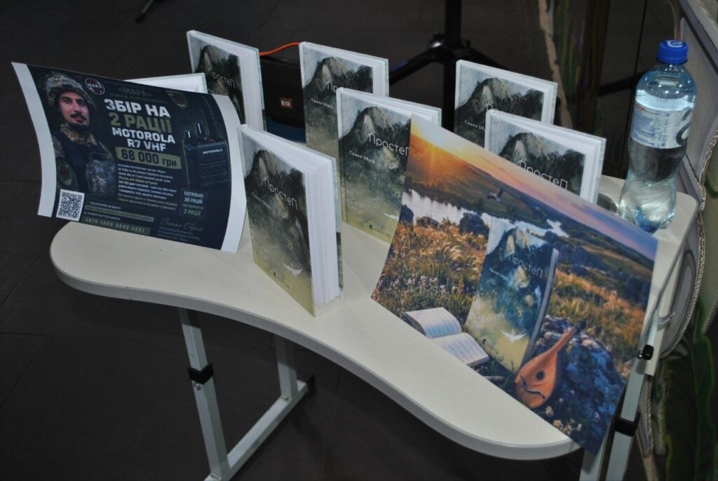 На стеліажі розміщено книги «ПростеП» та плакат із закликом «Збір на 2 ради Motorola R7 VHF».