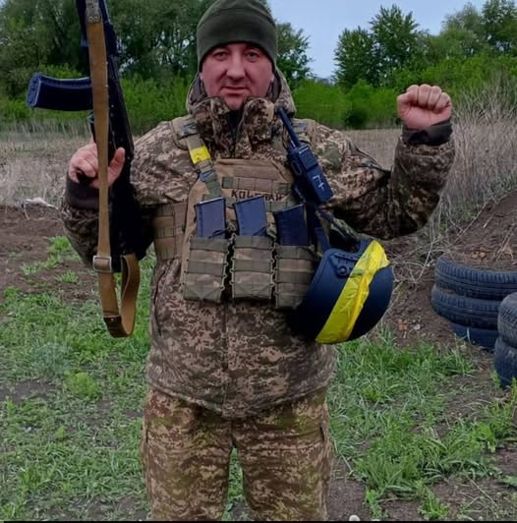 Бойовик у камуфляжі тримає автомат і піднімає кулак, на грудях напис 