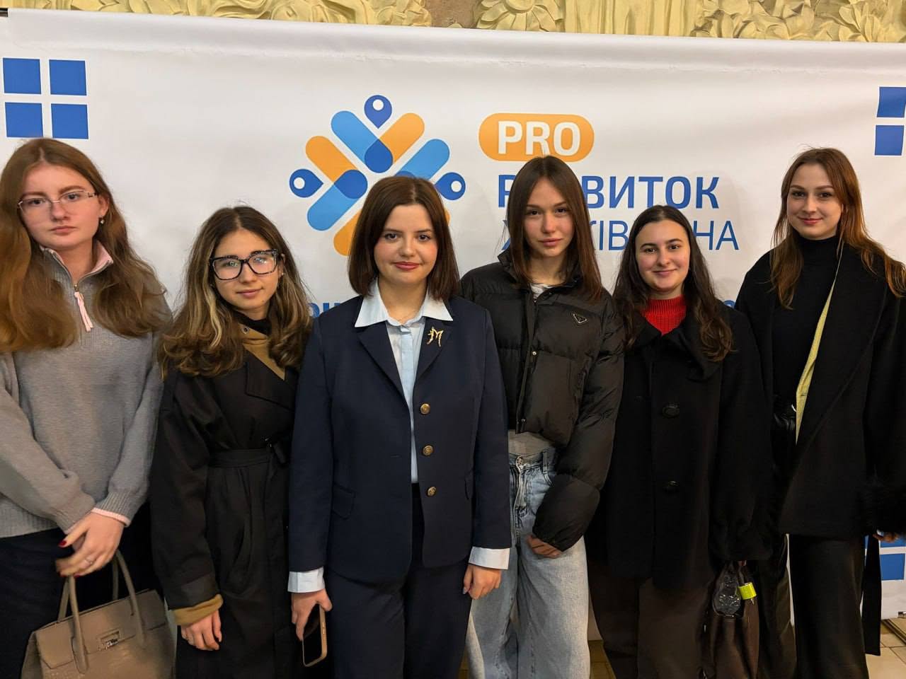Група молодих жінок стоїть перед банером з логотипом PRO та текстом «БУДІВНИК».