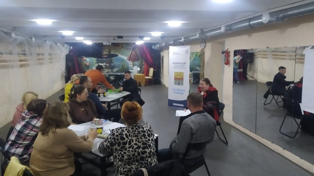 Учасники семінару обговорюють матеріали за столами в залі з дзеркалами та банером «Україна в ЄС».