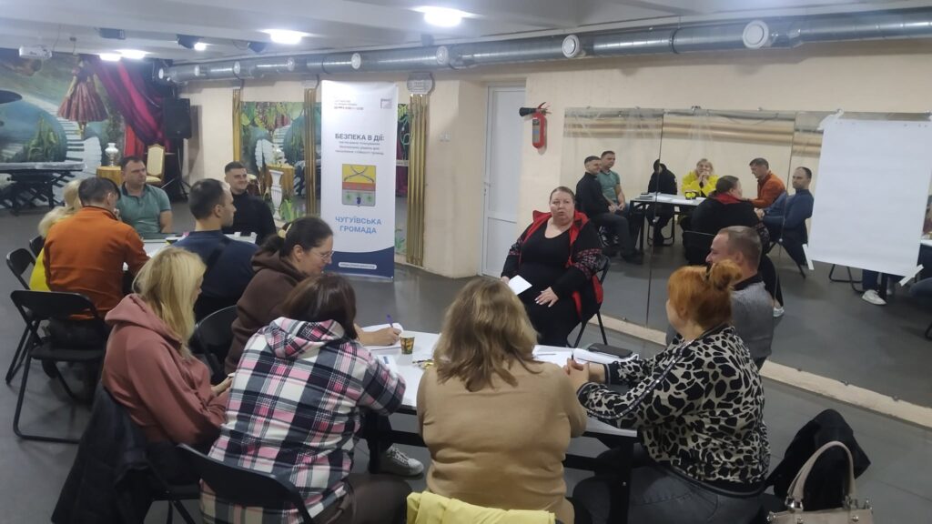 Учасники семінару слухають доповідачку біля банера з написом «Безпека в дії» та «Чутлівська громада».