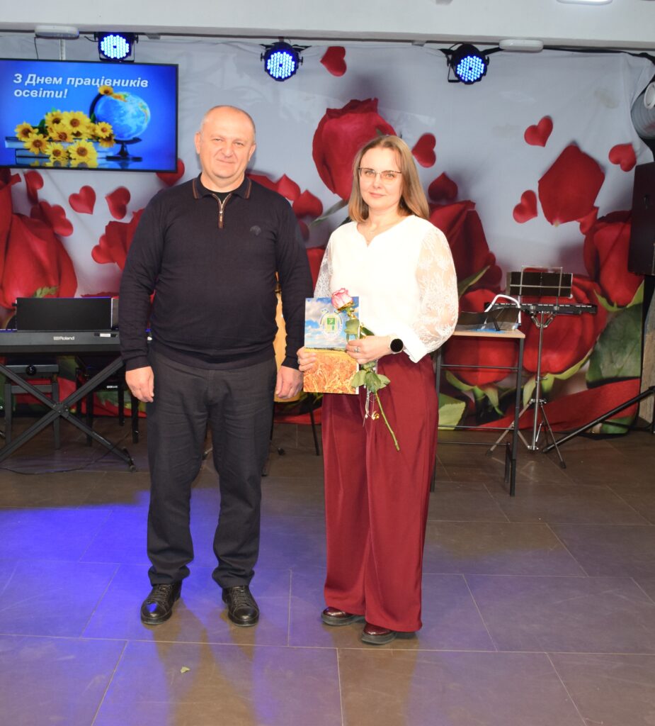 Чоловік і жінка тримають букет квітів на тлі екрана з написом «З Днем працівників освіти!
