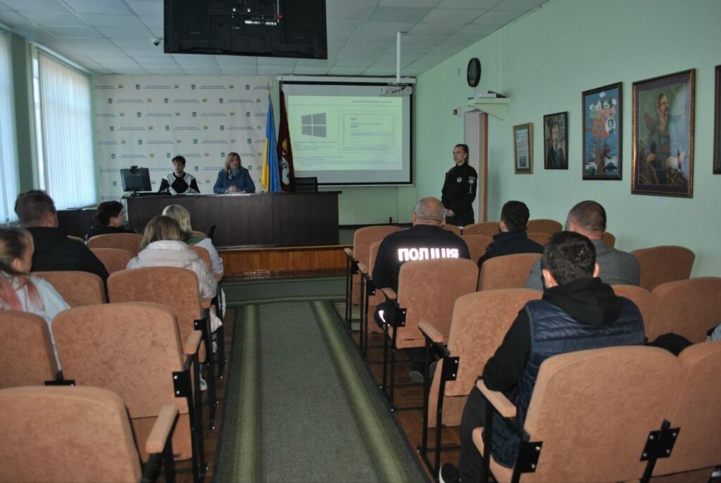 Публічне засідання в залі, де представники поліції та інші співробітники проводять презентацію для аудиторії.